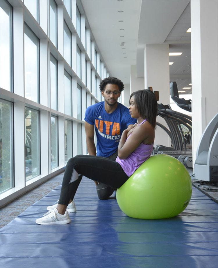 Personal Trainer instructing a woman doing situps on a ball
