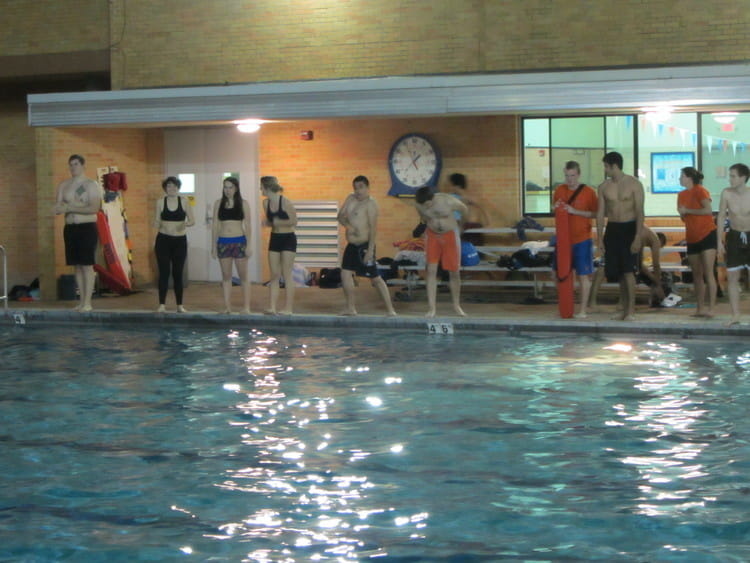 Students lined up the side of the indoor pool ready to jump in the freezing water