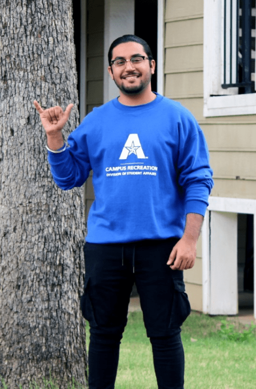 Gurvir wearing a campus rec sweatshirt giving a mav up hand sign
