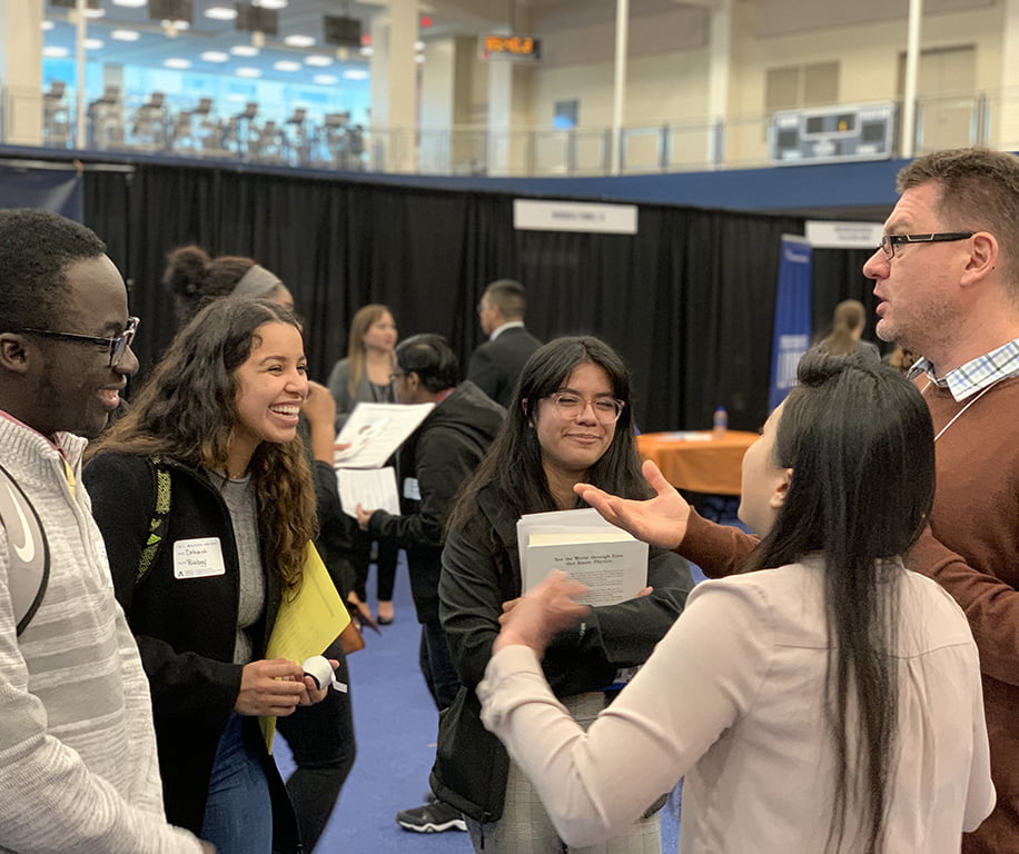 multiple students talking to a woman and a man