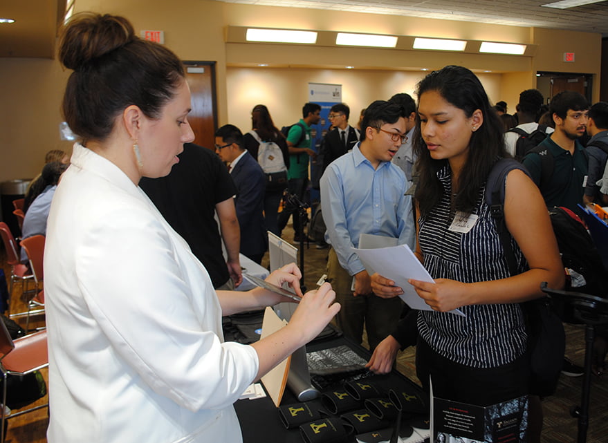 student talking to woman wearing white coat