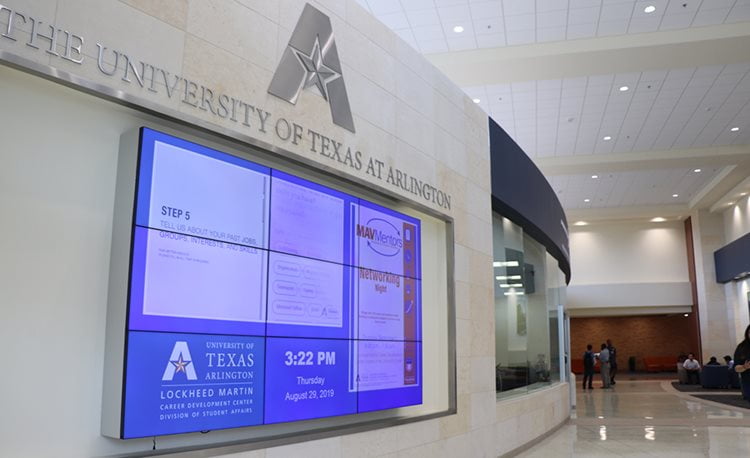 white wall with uta logo and blue noticeboard