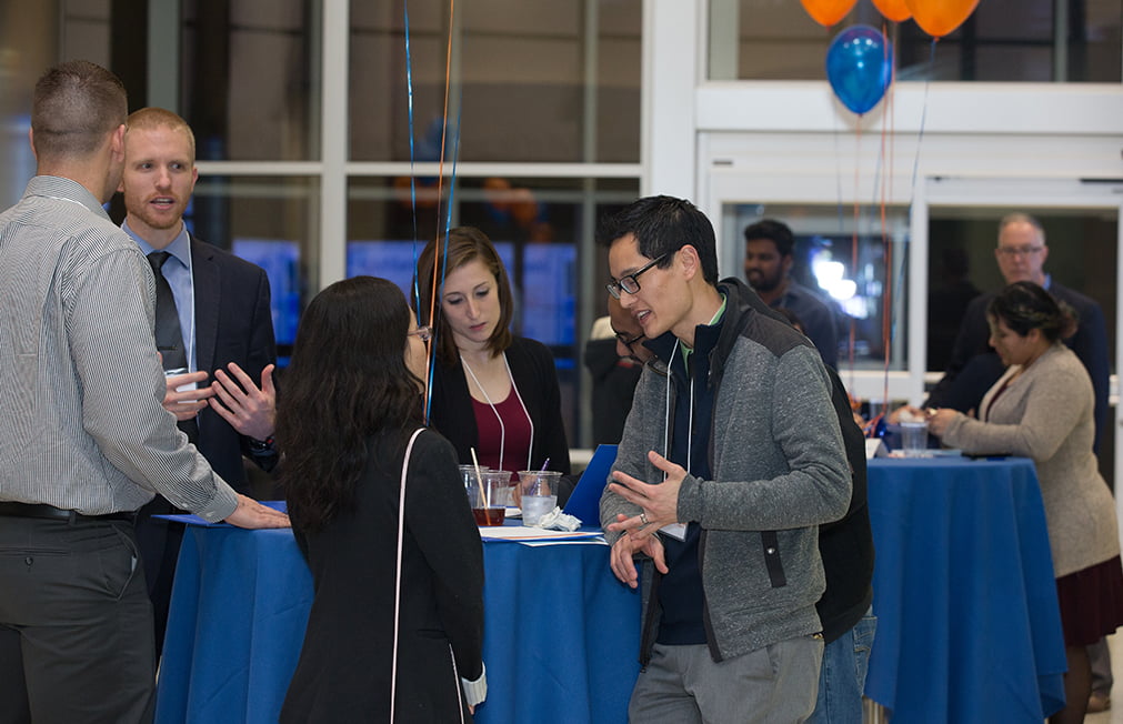 people talking in front of blue table and blue orange balloons