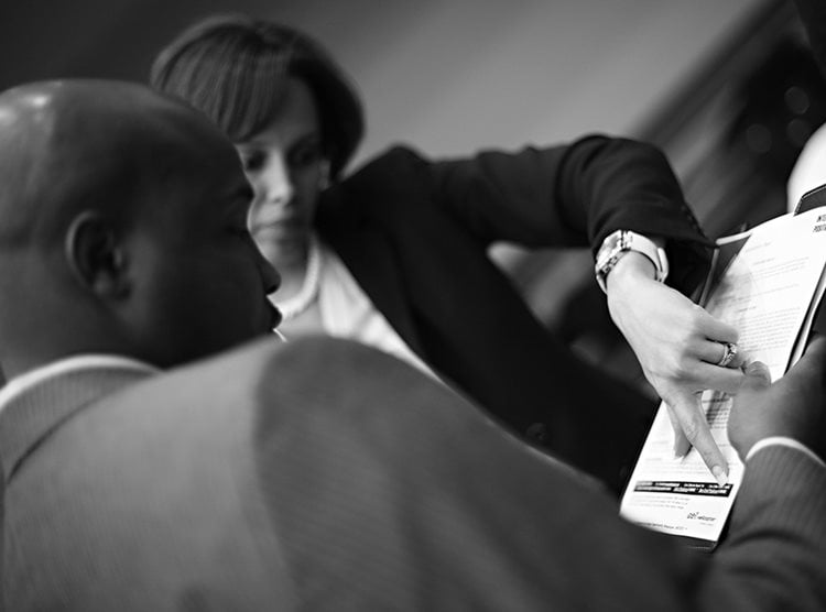 woman pointing to document in hand of student in blazer