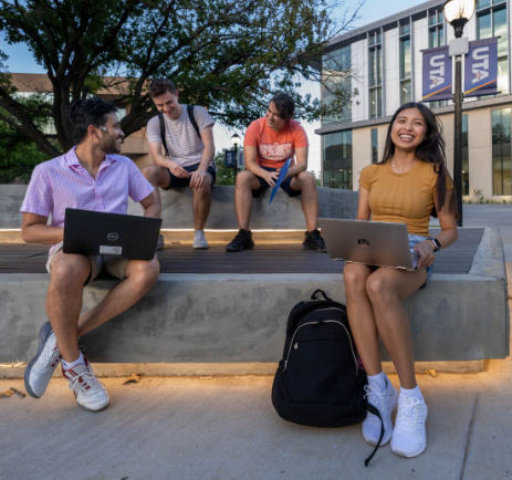 students on laptop outside library