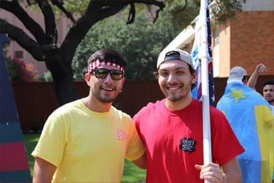 Two members of the Interfraternity Council holding various flags