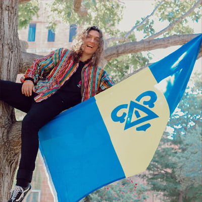 Fraternity member on a tree branch holding a flag