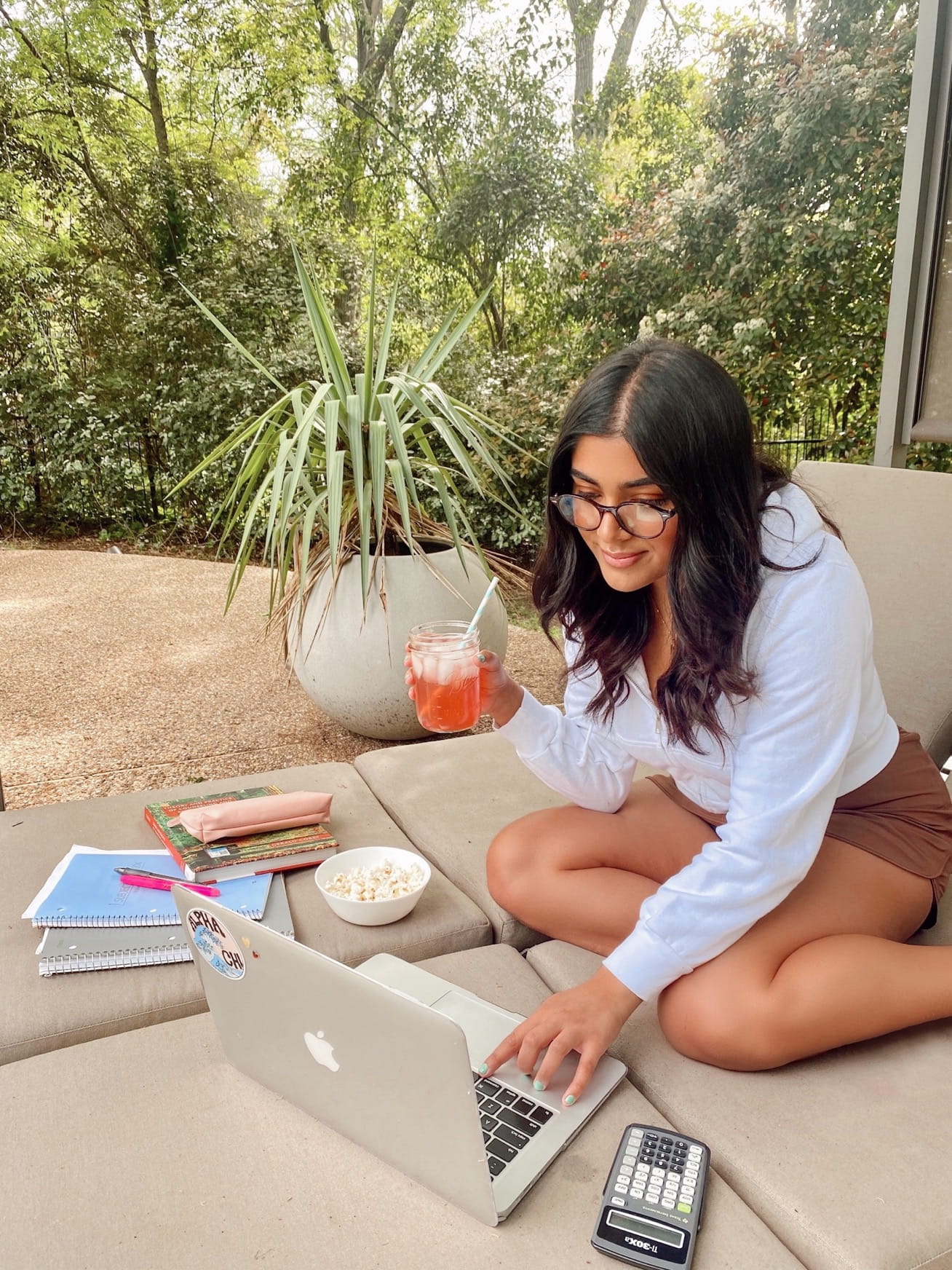 UTA student Hanna Lone on her computer next to plant