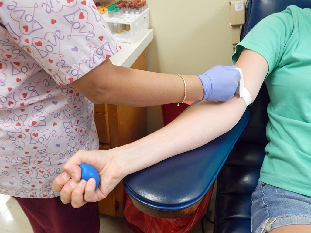 A patient on a chair with a blue squeeze ball in hand 