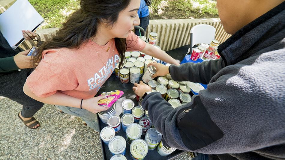A picture of two students arranging can food for food pantry distribution