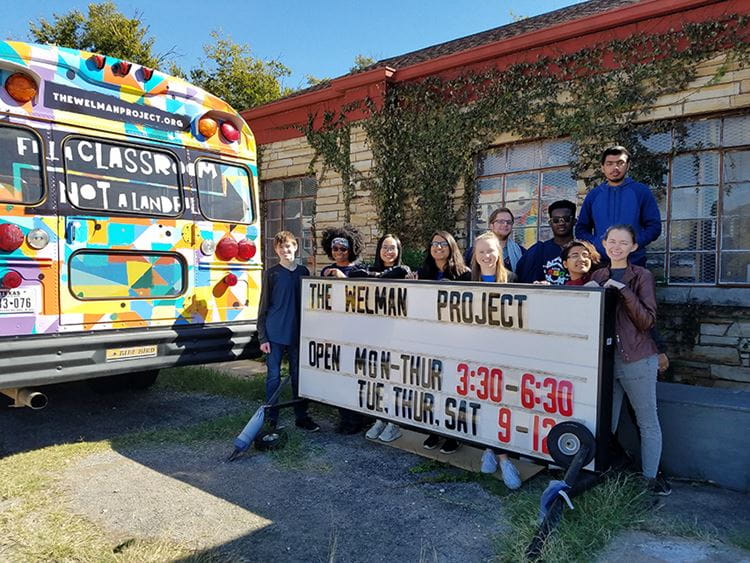 UTA Volunteers group at Wellman project posing with a colorful bus 