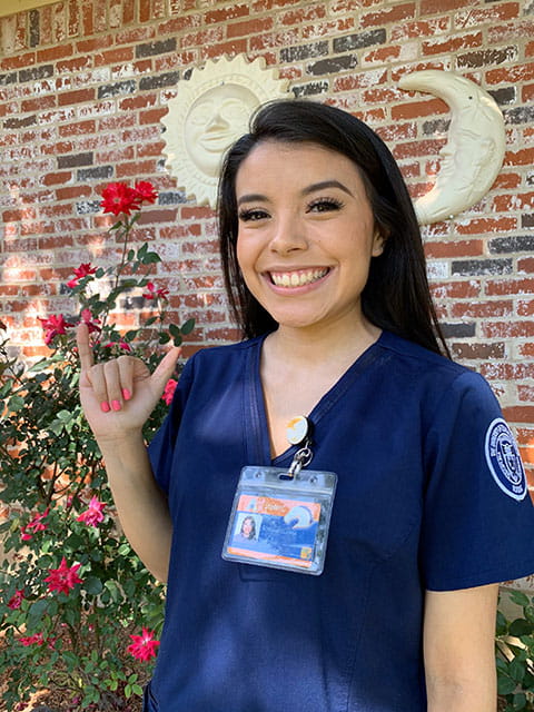 Nursing student Adriana Guerra holding pinky and thumb up in maverick salute.