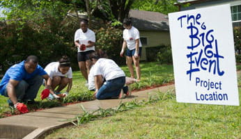 Volunteers gardening for The Big Event next to a sign labelled 'The Big Event Project Location'