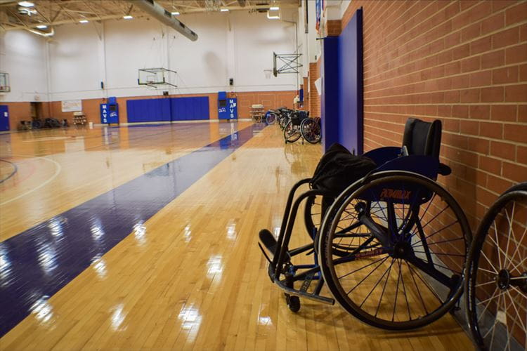 an empty wheelchair sitting in an empty gymnasium