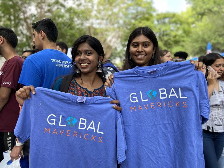 Photo of two students holding Global maverick T-shirts