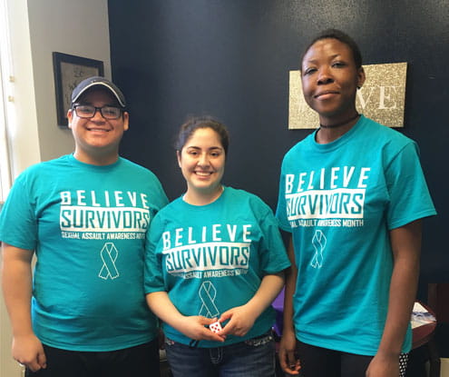 A man and two women wearing t-shirts labelled 'BELIEVE SURVIVORS SEXUAL AWARENESS MONTH"