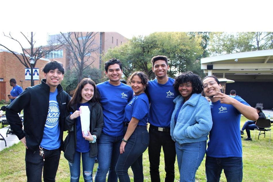 Excel members in their blue shirts standing in Brazos Park setting up an event
