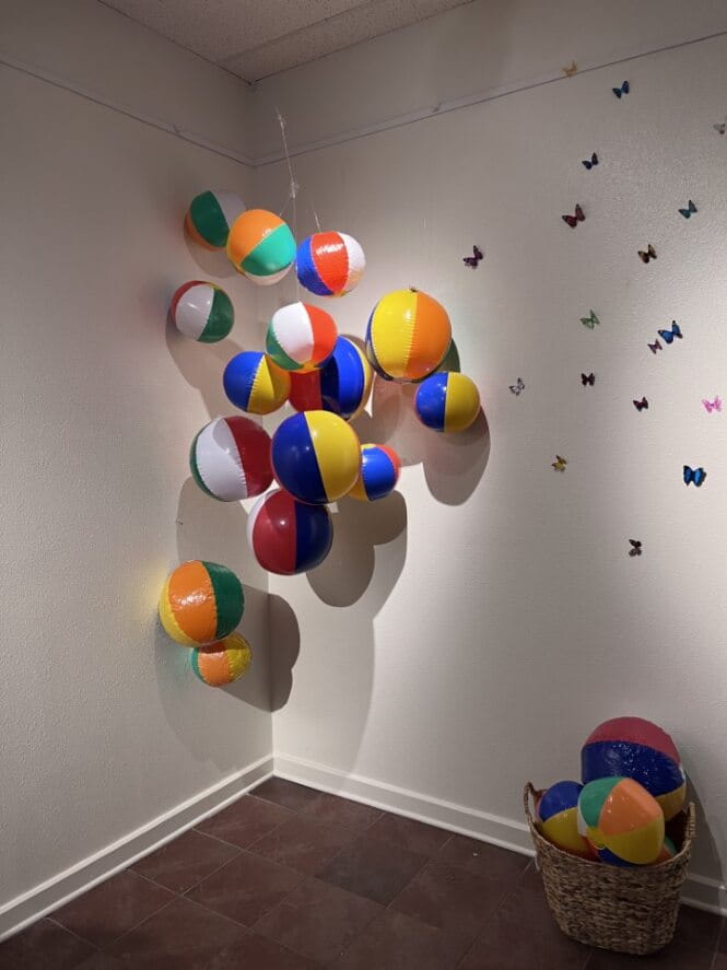 Picture of an artwork with balloons colored in orange, white, blue and green