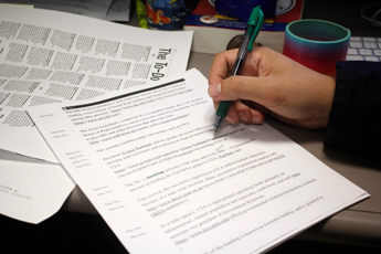 A hand of someone writing notes on a document at their desk