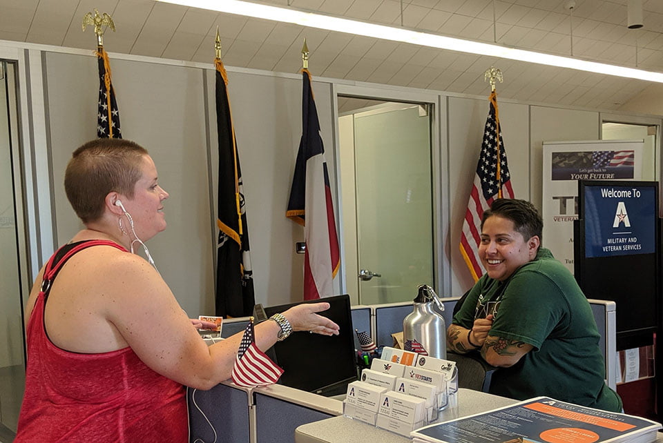 People chatting at check in in front of flags.