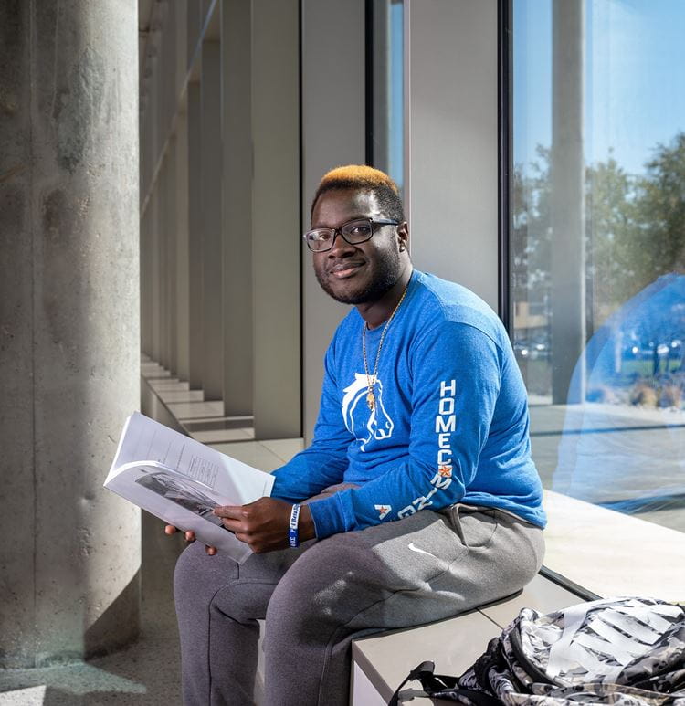 trevion sheppard sitting in a window reading on campus