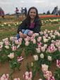 female student crouching down among the tulips